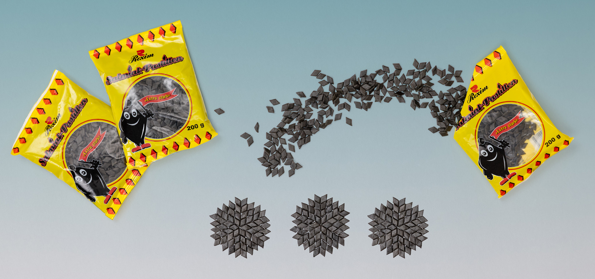 Foto von Salmiakpackungen und einzelnen Salmiakpastillen